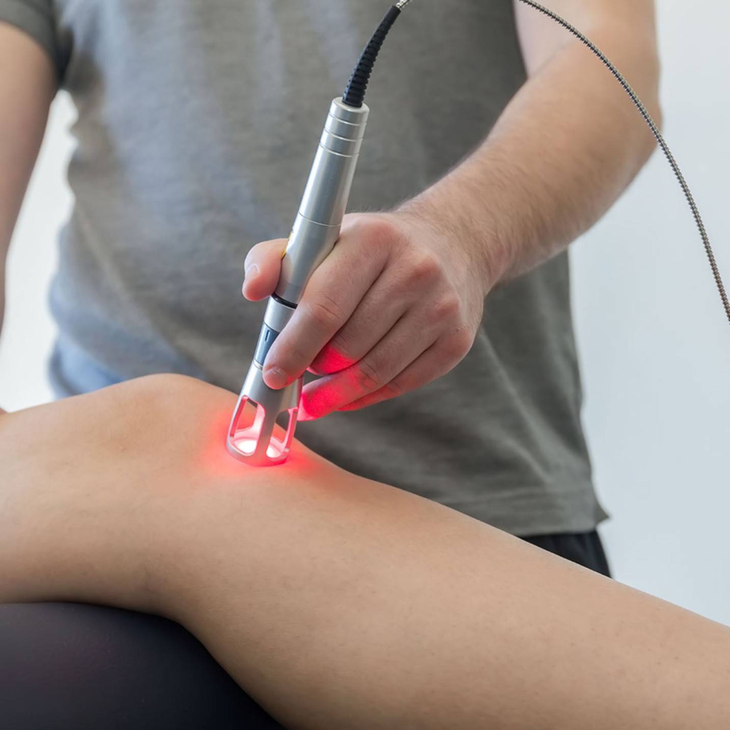 a doctor treating a knee joint with laser therapy.